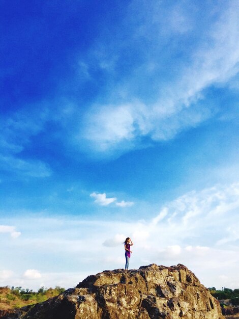 Foto mujer de pie en la roca contra el cielo