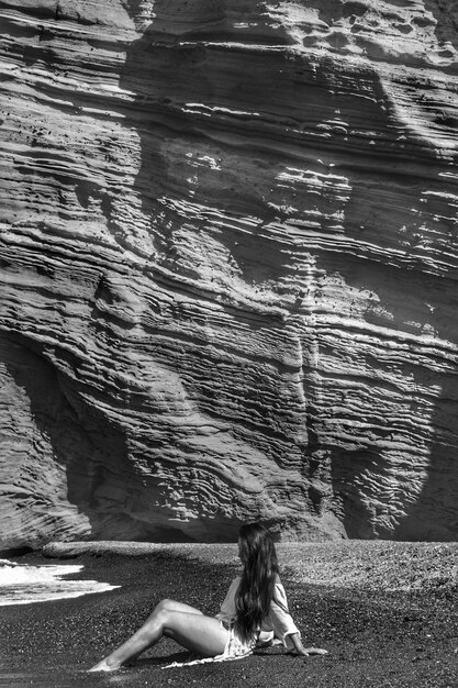 Foto mujer de pie en una roca junto al mar