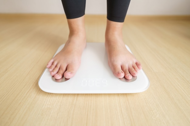 Mujer de pie sobre pesar balanzas electrónicas para comprobar el peso. concepto de estilo de vida de dieta para reducir