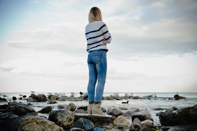 Mujer de pie sobre las rocas del mar y mirar hacia adelante