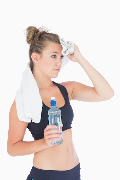 Mujer de pie sosteniendo una botella de agua y una toalla blanca