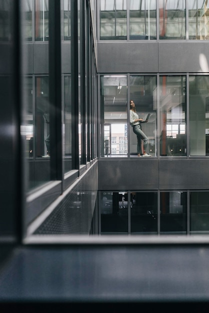 Mujer de pie en la ventana de la oficina