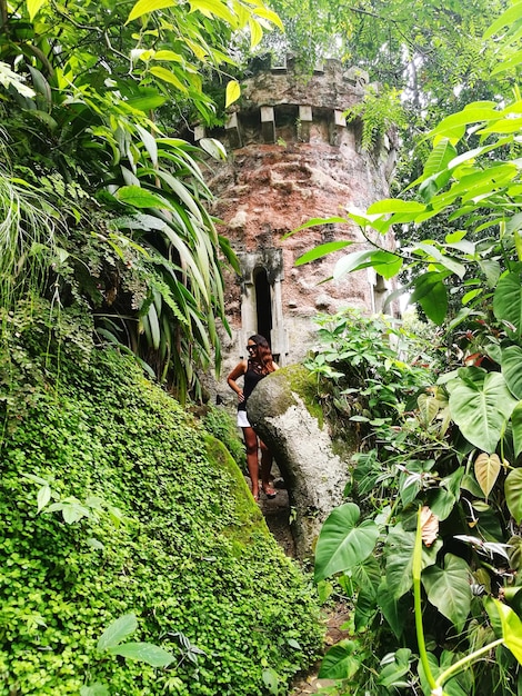 Foto mujer de pie en la vieja ruina en medio de las plantas