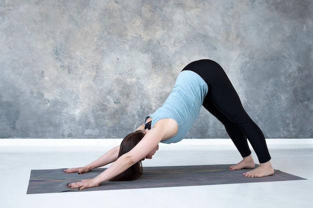 Mujer de pie en yoga perro boca abajo pose adho mukha svanasana