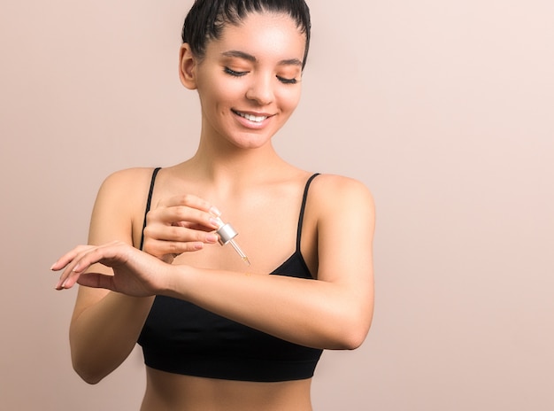 mujer con piel limpia aplicando aceite corporal en su brazo