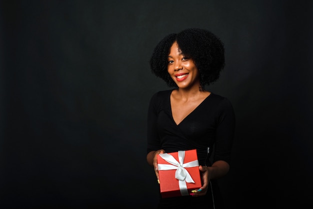 Una mujer de piel oscura con peinado afro da un regalo