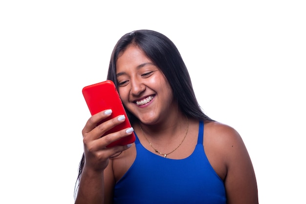 Mujer de piel oscura riendo y mirando el teléfono celular aislado sobre fondo blanco.