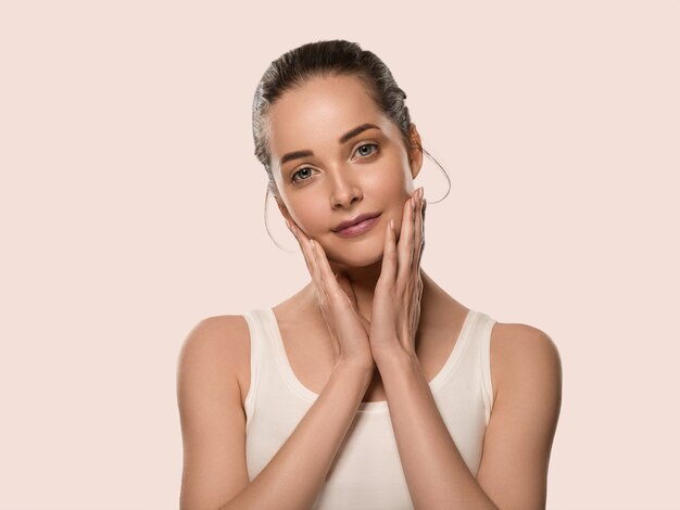 Mujer de piel sana de belleza tocando su rostro mujer hermosa. Fondo de color. Rosado