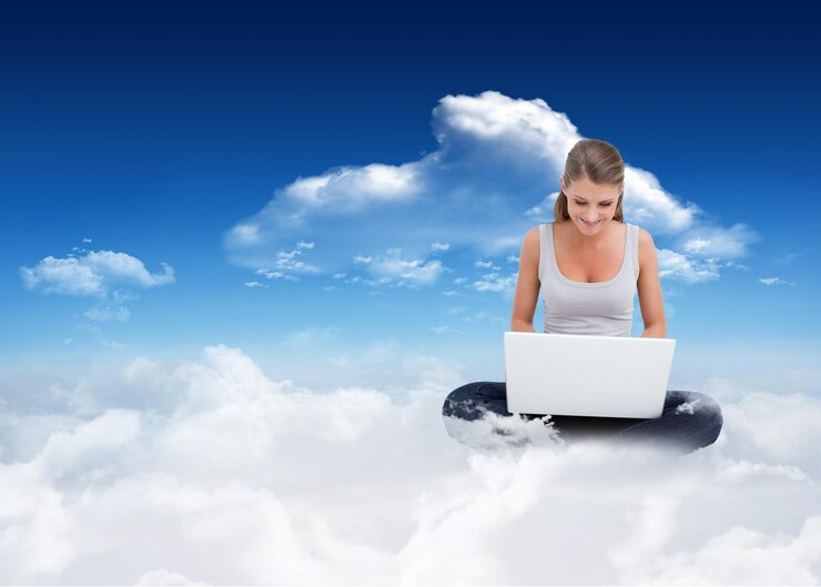 Foto mujer con las piernas cruzadas usando una computadora portátil contra el cielo azul brillante con nubes