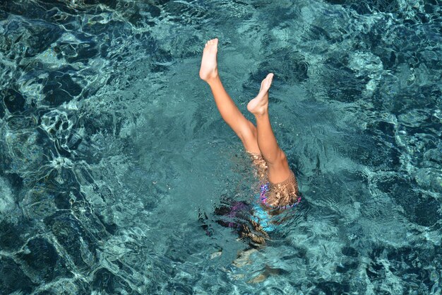 Foto mujer con los pies hacia arriba nadando en el mar