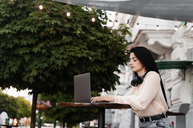 Mujer con pigmentación de la piel de vitíligo en las manos trabajando en una computadora portátil en línea al aire libre en un café Enfermedad estacional de la piel