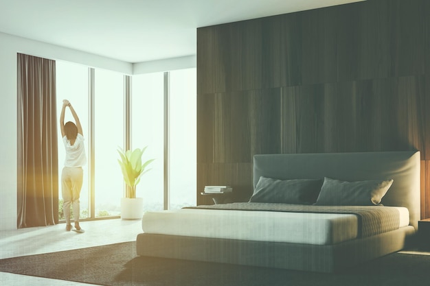 Mujer en pijama en un rincón de dormitorio de lujo con paredes de madera, suelo blanco y cama tamaño king. estilo escandinavo. Representación 3d simulacro de imagen tonificada doble exposición