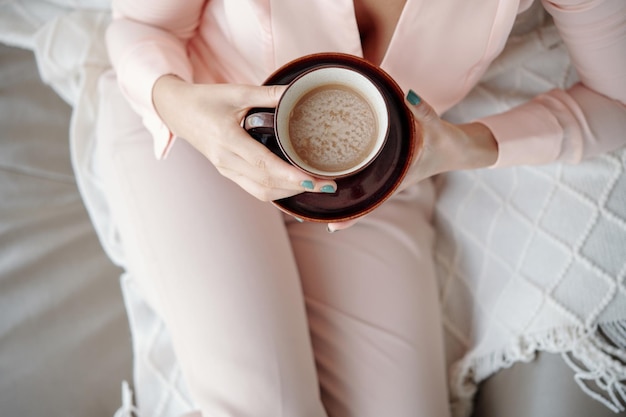 Mujer en pijama rosa claro sosteniendo una taza de delicioso cappunnino