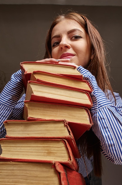 Una mujer con una pila de libros que quiere estudiar.