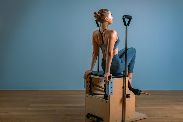 Mujer de Pilates en un reformador haciendo ejercicios de estiramiento en el gimnasio. Concepto de fitness, equipo de fitness especial, estilo de vida saludable, plástico. Copia espacio, banner deportivo para publicidad