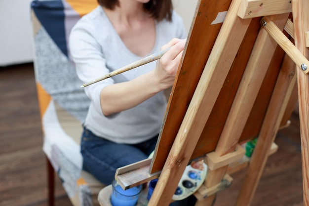 Una mujer pinta con pinturas en un primer plano de caballete