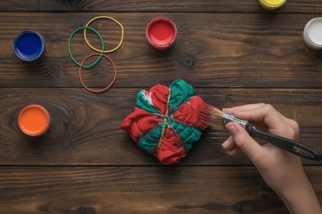 Una mujer pinta ropa estilo tie dye en rojo y verde. Tejido teñido en estilo tie dye.