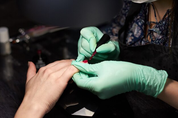 Mujer pinta uñas cliente. Manicura en las uñas.