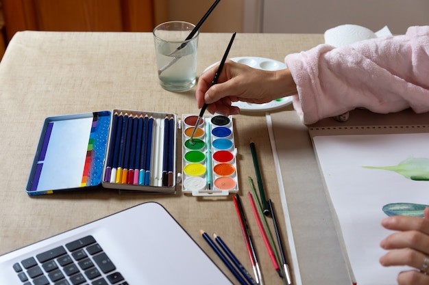 Mujer pintando con acuarelas en casa