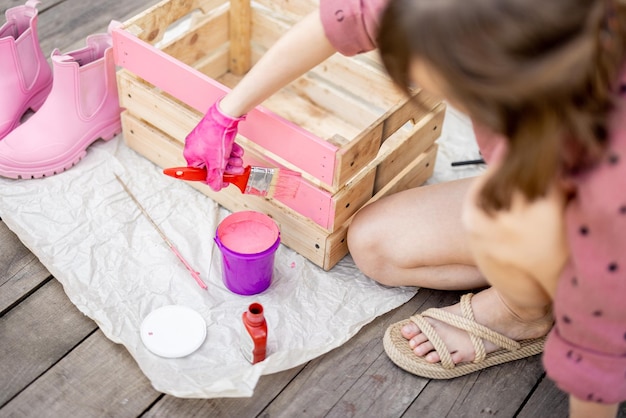 Mujer pintando caja de madera en color rosa concepto diy