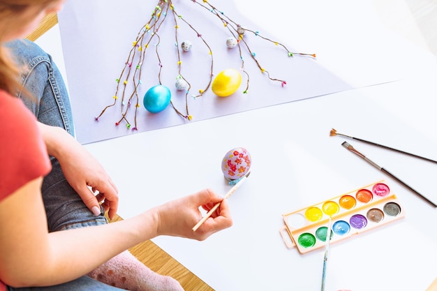 Una mujer pintando huevos de pascua en una mesa