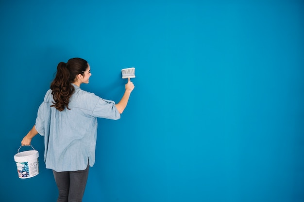 Foto mujer pintando pared azul