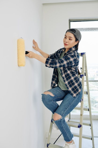 Mujer pintando la pared de la casa