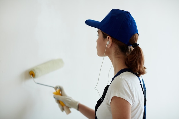 Mujer pintando paredes con música