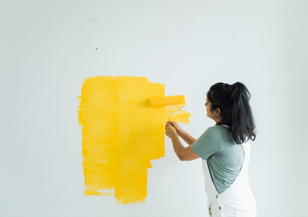 Mujer pintando sus paredes amarillas