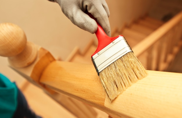 Mujer pintando una tabla de madera de barniz con pincel