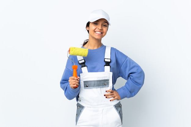 Mujer pintor sobre blanco aislado posando con los brazos en la cadera y sonriendo