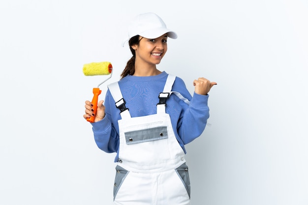 Mujer pintor sobre pared blanca aislada apuntando hacia el lado para presentar un producto