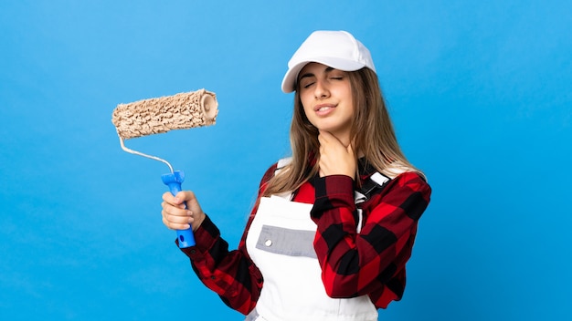 Mujer pintora sobre pared azul aislada tosiendo mucho