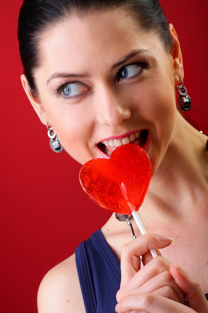 Foto mujer con piruleta roja en forma de corazón