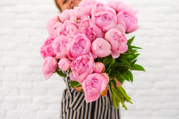 mujer con placer sostiene en las manos un ramo de peonías rosas