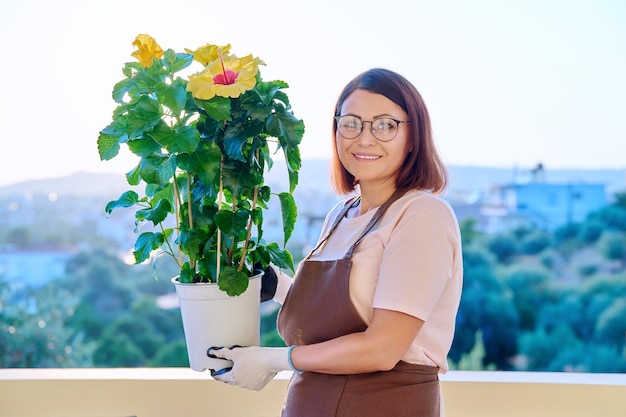 Mujer plantando cuidando una planta de casa en una maceta en la terraza