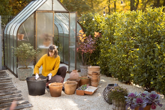 Mujer plantando flores en jarras en el jardín