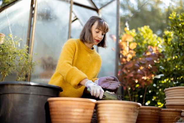 Mujer plantando flores en jarras en el jardín