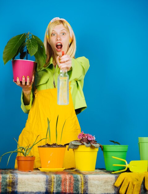 Mujer plantando flores en maceta. Regando las flores. Mujer jardinero plantando flores. Jardinería rubia linda en el fondo aislado.