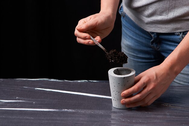 Mujer plantando suculentas en olla de concreto.