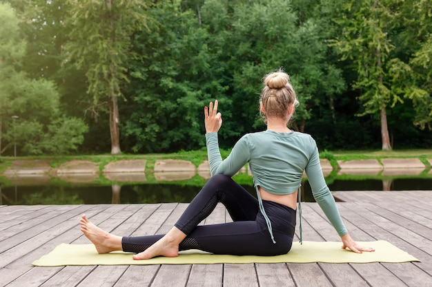 Una mujer en una plataforma de madera en verano hace yoga