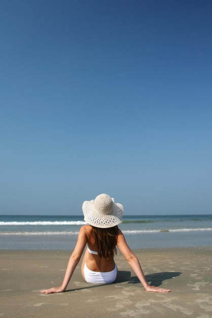 Mujer en la playa cerca del mar y cielo azul