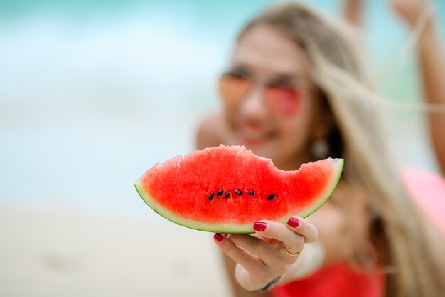 Mujer en la playa come comida vegetariana en la costa del océano