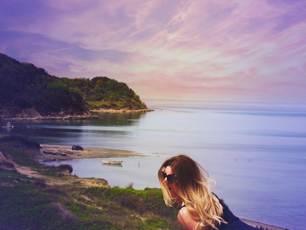 Foto mujer en la playa contra el cielo durante la puesta de sol