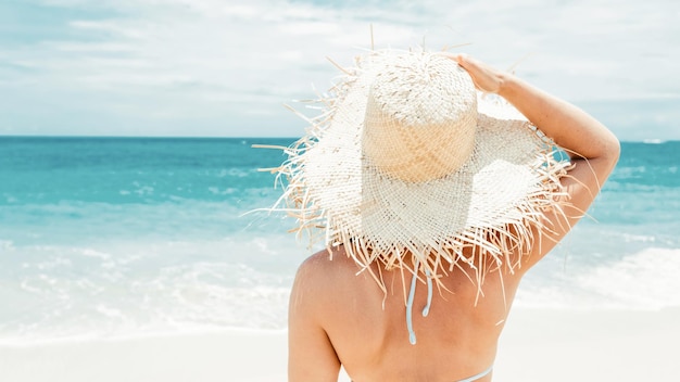 mujer en la playa con un sombrero blanco