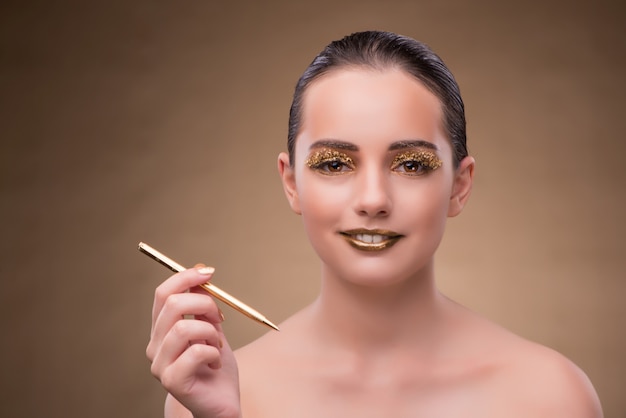 Mujer con pluma de oro en concepto de moda