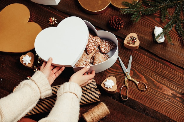 Mujer pone galletas en una caja con regalos alrededor