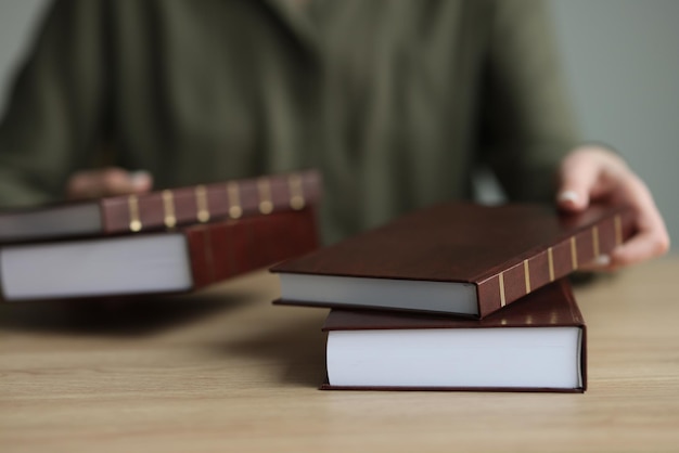 Mujer pone gruesos libros de historia con tapa dura marrón en la mesa de madera bibliotecario da material