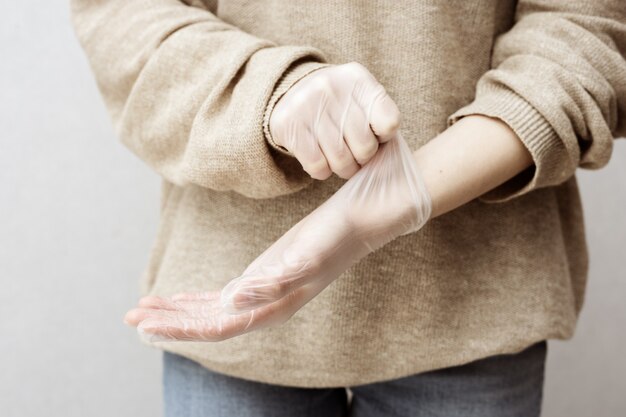 La mujer se pone guantes de goma para protegerse las manos