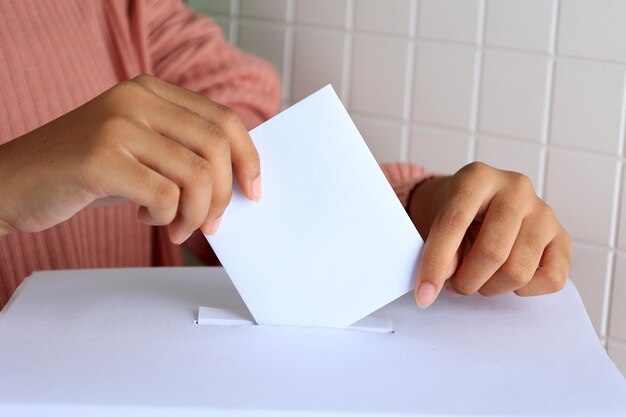 Mujer pone a mano la tarjeta de voto en la urna